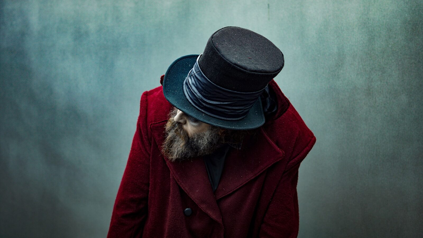 A person wears a top hat and red coat